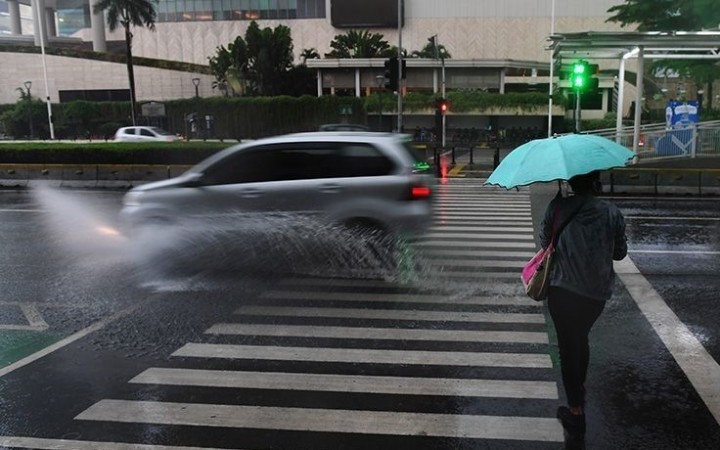 Warga menggunakan payung untuk menghindari hujan saai menyeberangi jalan di kawasan Bundaran Hotel Indonesia, Jakarta.