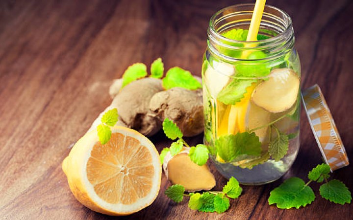 Segelas infused water jahe lemon segar dengan potongan jahe dan irisan lemon, minuman sehat untuk detoks tubuh