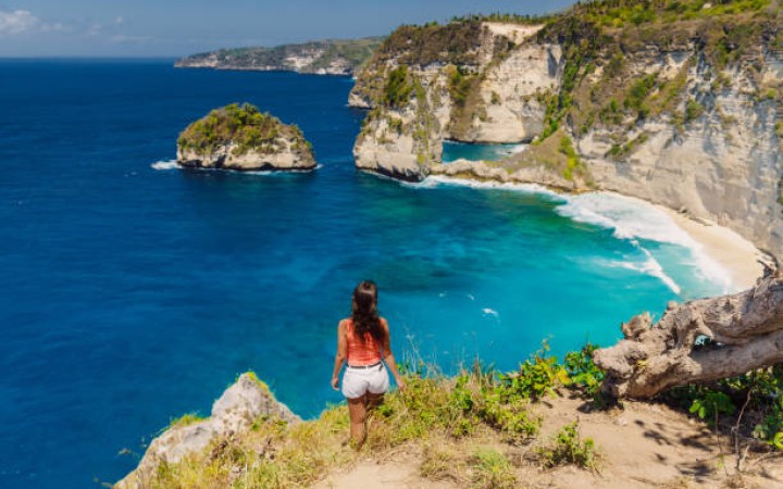 Ilustrasi: Gadis perjalanan di laut, tebing, dan latar belakang pantai tropis. Nusa Penida, Indonesia (foto: gemabali/ istock)